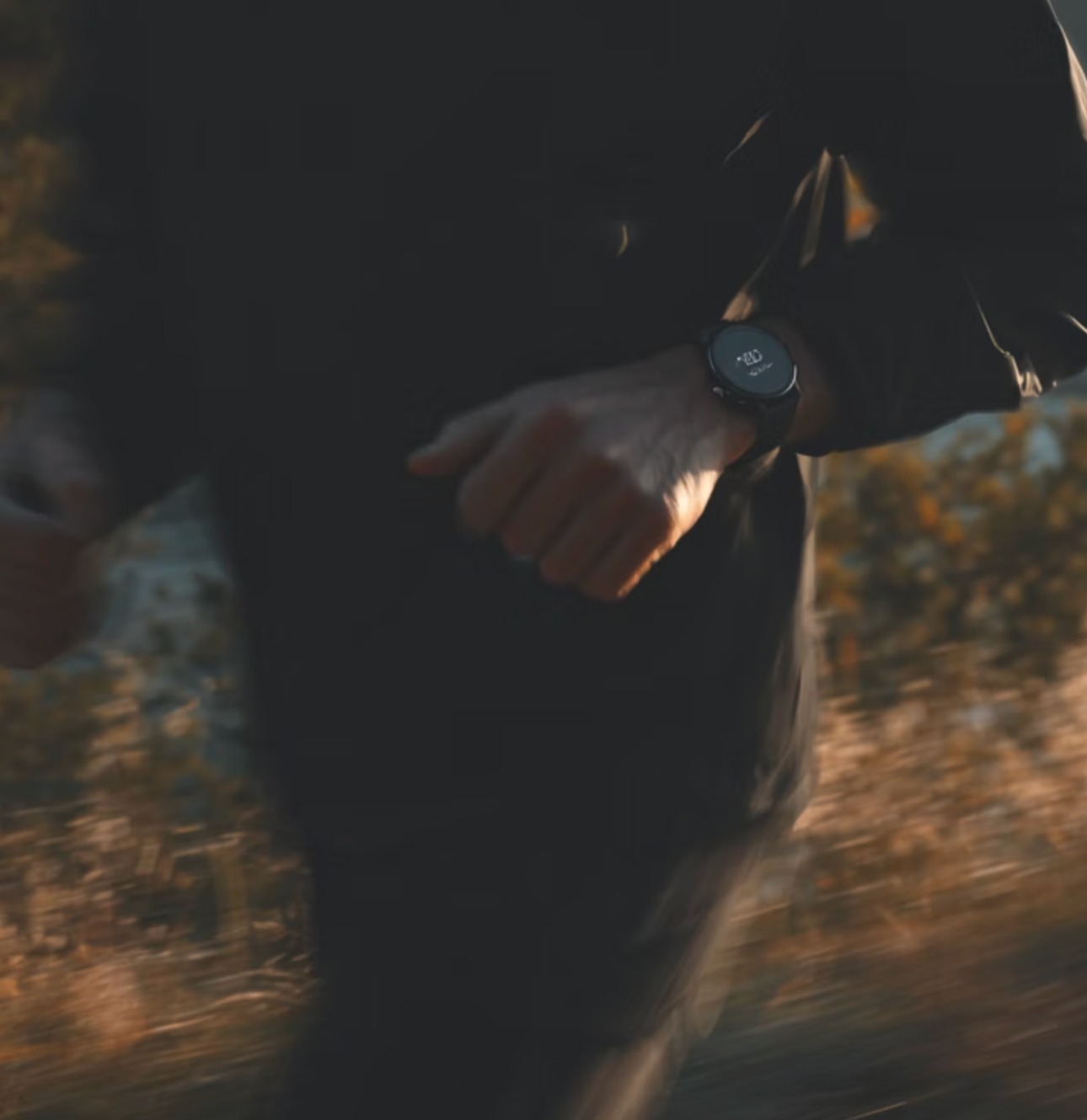 Runner on a trail at golden hour wearing a fitness watch